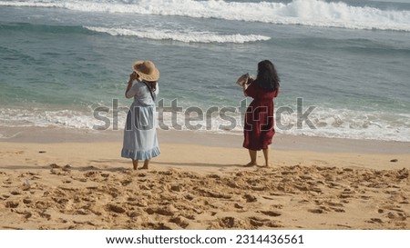 two people taking pictures on the beach
