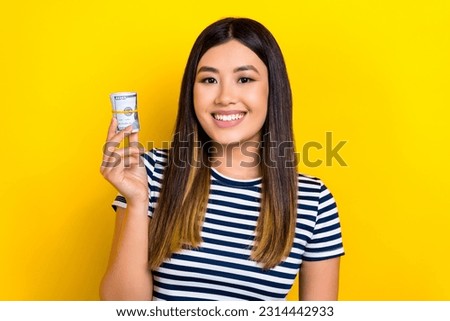 Photo of cheerful positive lady wear striped dress smiling holding cash roll isolated yellow color background
