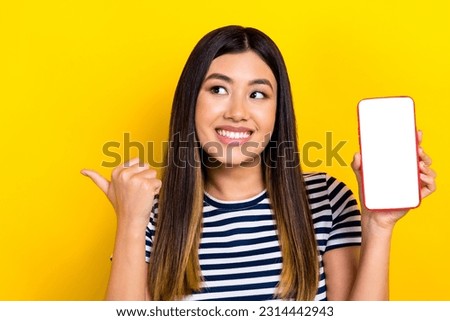 Photo of chinese funny woman wear striped t-shirt direct finger empty space hold advert promo display isolated on yellow background