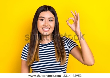 Portrait of young korean woman wear striped t-shirt show okey sign nice feedback work job result rate isolated on yellow color background