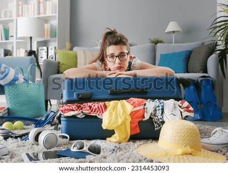 Tired sad woman packing for a long journey, she is leaning on her overloaded trolley bag: travel, vacations and tourism concept Royalty-Free Stock Photo #2314453093