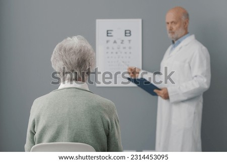 Senior woman having an eye exam with a professional oculist, she is sitting and looking at the eye chart Royalty-Free Stock Photo #2314453095