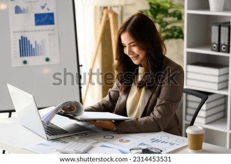 Charming asian woman startup business founder using laptop computer, working with reports at workplace
