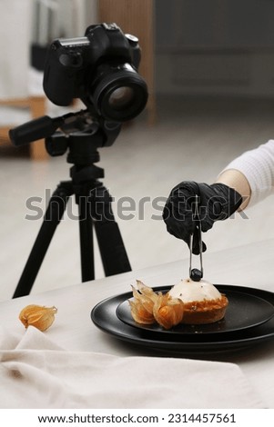 Food stylist creating beautiful composition with delicious dessert on white wooden table in photo studio, closeup