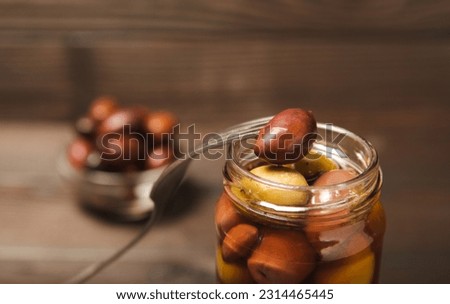 Close-up of olives on fork and glass jar on the kitchen table. pitted green olives in jar.Pickled olives in glass jar. On a wooden background.Marinaded olives. Space for text.Space for copy. 