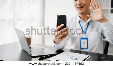 Businessman hand using smart phone laptop and tablet with social network diagram on desk as concept in morning light.
