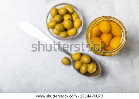 Olives in a glass jar on a concrete background. pitted green olives in jar.Pickled olives in glass jar. On a wooden background.Marinaded olives. Space for text.Space for copy. Vegan food.