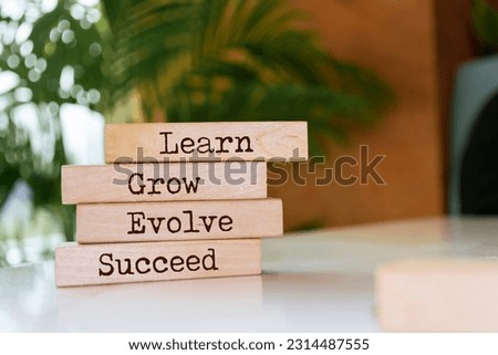 Wooden blocks with words 'Learn, Grow, Evolve, Succeed'.