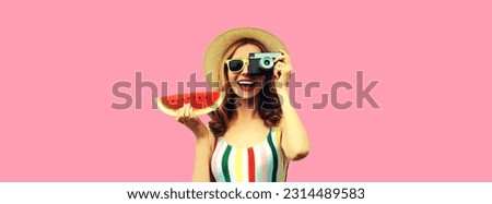 Summer portrait of happy smiling young woman with film camera and slice of fresh watermelon wearing straw hat on pink background