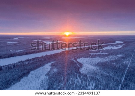 The northern sun is low on the horizon. Landscape of winter taiga. Russian winter of northern latitudes from a drone.