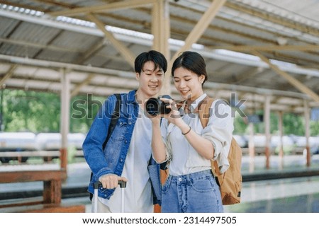 Young couple traveling using a camera to capture memories while waiting for the train at the station.travel concepts