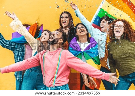 Diverse group of young people celebrating gay pride festival throwing confetti in the air - Lgbt community concept with guys and girls hugging together outdoors Royalty-Free Stock Photo #2314497559