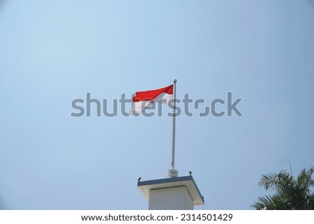 The Indonesian flag is waving above an old building, symbol of patriotism