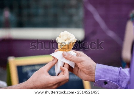 Waffle cone with ice cream, two hands are drawn to summer pleasure. Background with colorful bokeh. Real scene in  store