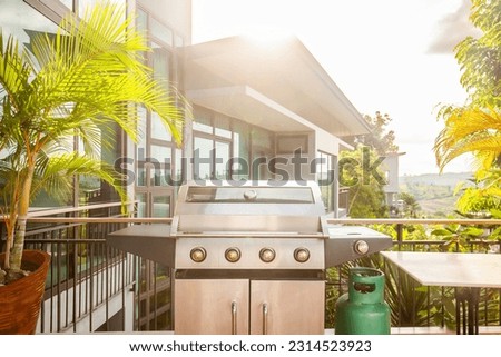 Modern luxury patio with a large grill for summer barbecues in a backyard deck. The gas BBQ and stylish furniture provide a perfect setting to cook, relax, and enjoy the outdoors. Royalty-Free Stock Photo #2314523923