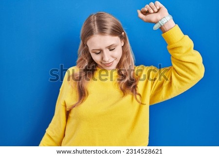 Young caucasian woman standing over blue background dancing happy and cheerful, smiling moving casual and confident listening to music 