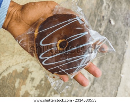 Dark chocolate donut in plastic wrap
