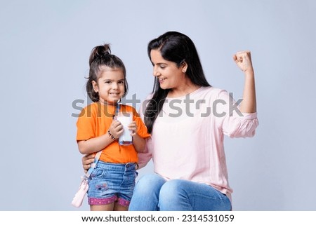 Indian mother giving milk in glass his daughter on white background. Royalty-Free Stock Photo #2314531059