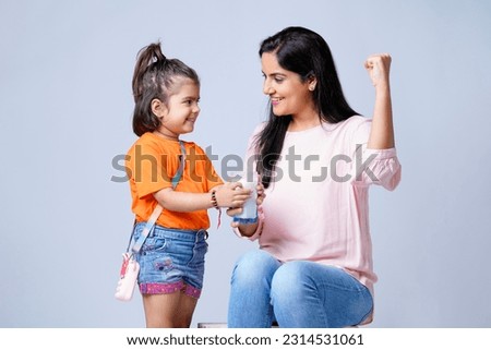 Indian mother giving milk in glass his daughter on white background. Royalty-Free Stock Photo #2314531061