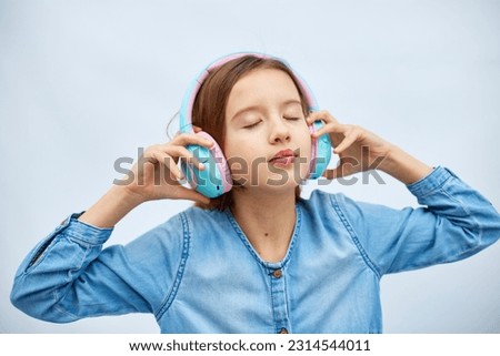 Girl teenager with close eyes listening to music in headphones on white background, wireless earphones enjoying music , Modern technology, Protect Developing Ears