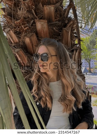 Girl in glasses. Posing, model. Photo next to the palm tree