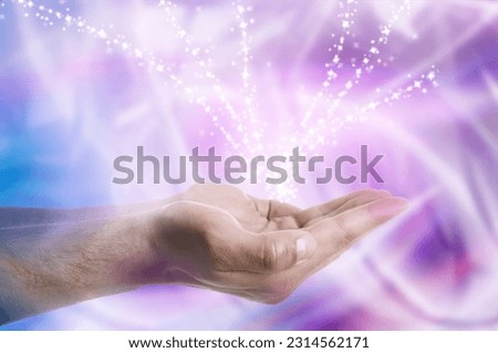 Aura phenomena. Man with flows of energy around his hands and lights flying out against color background, closeup Royalty-Free Stock Photo #2314562171