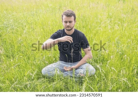 Meditation in the fresh air. Meditating young man. Relaxation on the grass