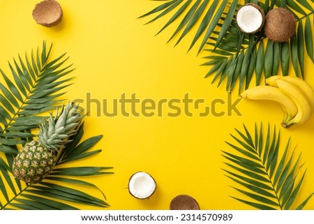 Yearning for sunny days. Top view of palm leaves and tantalizing exotic fruits on a vibrant yellow background with space for text or advertorial content