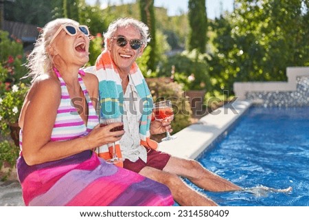 Portrait happy, retired, carefree senior couple laughing and drinking cocktails at sunny summer swimming pool, enjoying vacation getaway Royalty-Free Stock Photo #2314580409