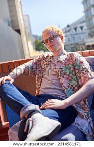 Portrait confident, cool young albino man on sunny rooftop Royalty-Free Stock Photo #2314581171