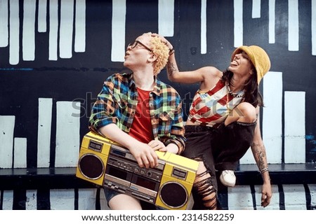 Happy, playful young couple with yellow ghetto blaster at painted wall Royalty-Free Stock Photo #2314582259