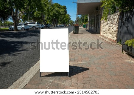 Background texture of a blank white advertisement board on walkway. Mockup template of a standing easel on pedestrian sidewalk in an small Australian regional town.