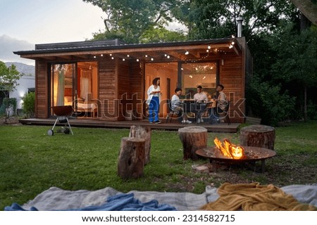 Couple friends enjoying barbecue dinner at patio table in summer backyard with fire pit