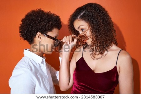 Portrait cool lesbian couple with curly hair in sunglasses face to face on orange background Royalty-Free Stock Photo #2314583307