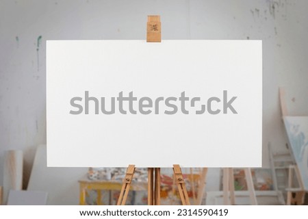 Blank canvas on easel in an artist's studio.