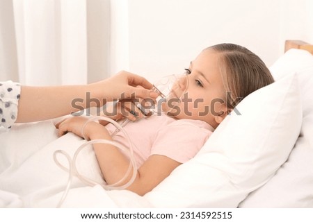 Mother helping her sick daughter with nebulizer inhalation in bedroom Royalty-Free Stock Photo #2314592515