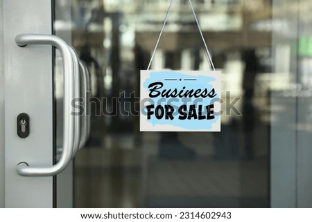 Light blue sign with Business For Sale hanging on glass door