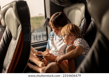 Children, siblings, playing on a mobile phone while traveling with bus on a long trip journey, family vacation Royalty-Free Stock Photo #2314606479