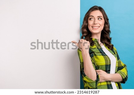 Photo of charming dreamy woman dressed plaid shirt looking thumb back poster empty space isolated blue color background