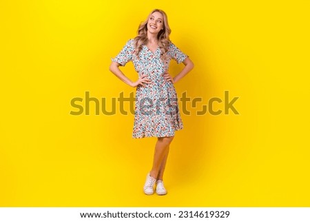Full length photo of cheerful dreamy lady wear flower print dress looking empty space isolated yellow color background