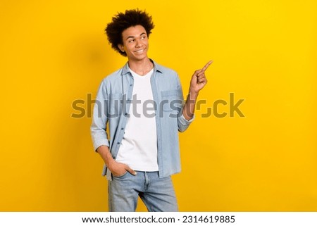 Photo of charming dreamy man wear jeans shirt looking showing finger empty space isolated yellow color background