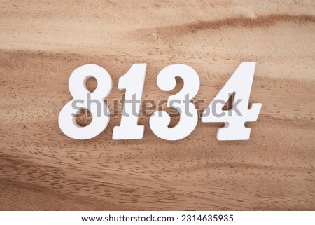 White number 8134 on a brown and light brown wooden background.
