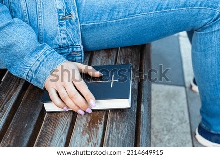 woman holding her hand on the bible lying on the bench. woman holding paper bible. High quality photo