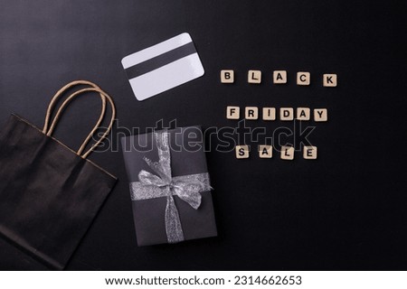 Wooden blocks forming words Black Friday Sale with paper bag, credit card and gift box on black background. Shopping concept and Black Friday composition.