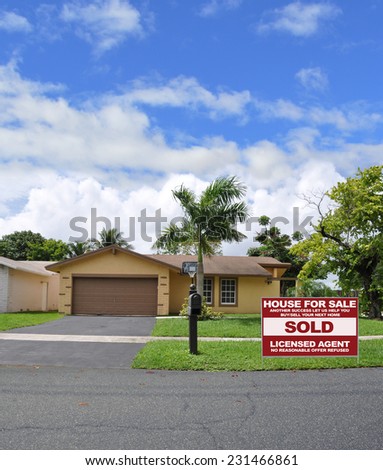 Real Estate Sold (another success let us help you buy sell your next home) sign suburban ranch style home palm tree residential neighborhood beautiful blue sky clouds USA