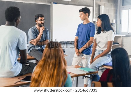Group of teenagers and male teacher at classroom talking and discussing together Royalty-Free Stock Photo #2314669333