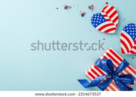 Armed Forces Day jubilation. Top view of representative adornments: hearts featuring USA flag design, shimmering confetti, thematic giftbox, on pastel blue surface with empty circle for text or promo