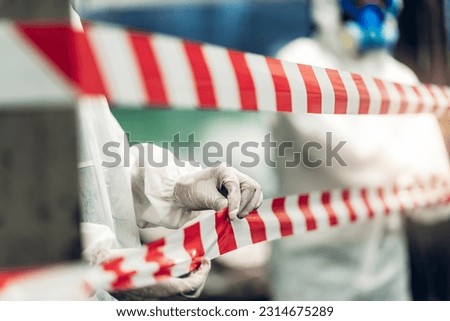 Scientist wear Chemical protection suit check danger chemical, working at dangerous zone in Red and White Lines of barrier tape. Red and white Hazardous restricted area factory safety worker industry Royalty-Free Stock Photo #2314675289