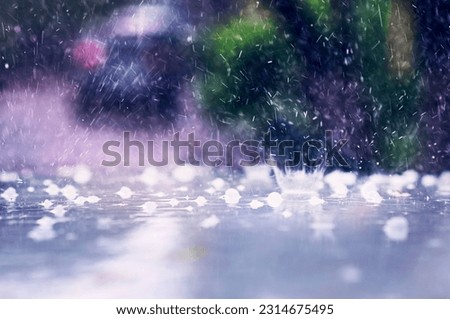 Heavy rain with hail hits the roof of the car. Splashes and fragments of ice are blurred in motion. The concept of climate change. Driving on rainy days. Selective focus. Royalty-Free Stock Photo #2314675495