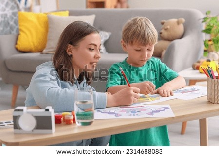 Nanny with little boy drawing at home Royalty-Free Stock Photo #2314688083